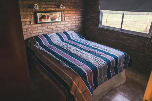 洛斯雷特斯El Retiro - Casa de campo en Los Reartes的砖墙房间的一个床位