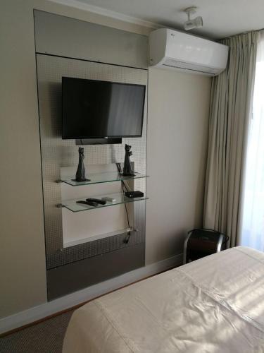 圣地亚哥Austral Rentahome Republica Árabe de Egipto的酒店客房设有一张床和壁挂式平面电视。