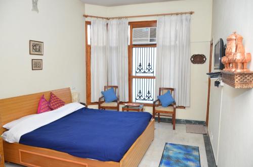 贾姆穆Sandy's Homestay的一间卧室配有一张床、两把椅子和一个窗户