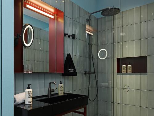 美因河畔法兰克福特瑞普25小时酒店的浴室配有盥洗盆和带镜子的淋浴