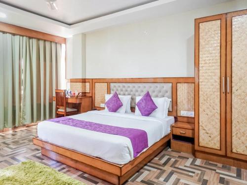 古瓦哈提Pemaling Lords Eco Inn Guwahati的一间卧室配有一张带紫色枕头的大床
