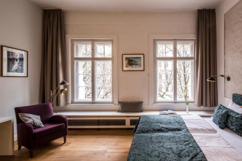 柏林奥德贝格酒店的一间卧室配有一张床和一把椅子,还有两个窗户