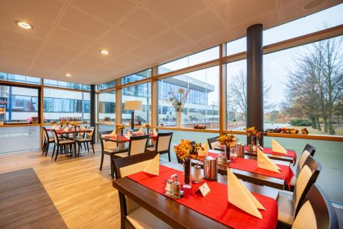 罗斯托克Das Hotel an der Stadthalle - Rostock Hauptbahnhof的餐厅设有桌椅和大窗户。
