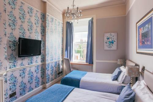 爱丁堡Braid Hills Hotel的客房设有两张床和一台墙上的电视。