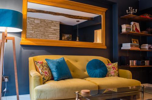 赛伦塞斯特Cotswold Place的客厅里一张黄色的沙发,配有镜子