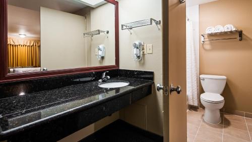 埃尔卡洪Rancho San Diego Inn & Suites的一间带水槽、卫生间和镜子的浴室
