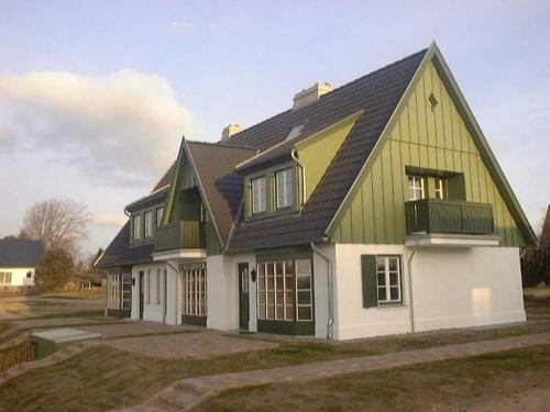 于克里茨Haus am Achterwasser Whg "Klabautermann"的黑屋顶的绿色白色房子