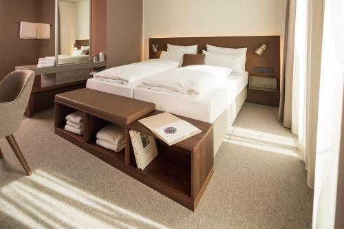 多瑙河畔诺伊堡Das ACKER Hotel的一间卧室配有一张床、一张桌子和一张四柱床。