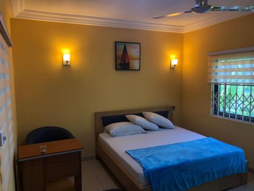 阿克拉Bonsukoda Lodge的一间卧室配有一张床、一张书桌和一个窗户。