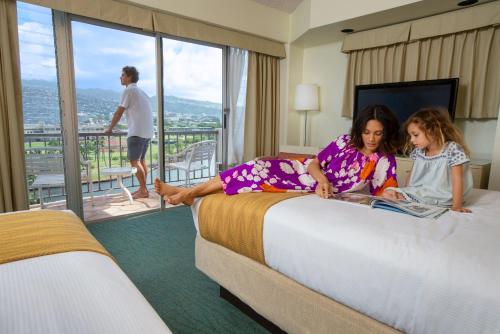 檀香山Coconut Waikiki Hotel的两名年轻女孩坐在酒店房间的床边
