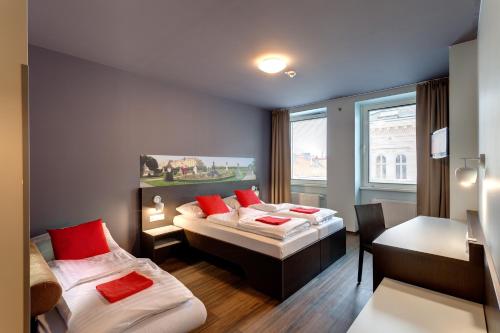 维也纳熙喜市中心梅宁阁酒店的客房设有两张床、一张桌子和一张书桌。