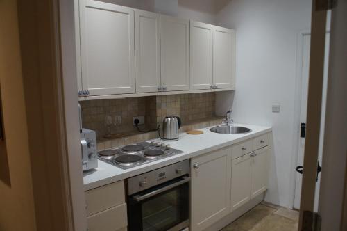 布里奇诺斯Bridgnorth B&B的厨房配有白色橱柜、炉灶和水槽。