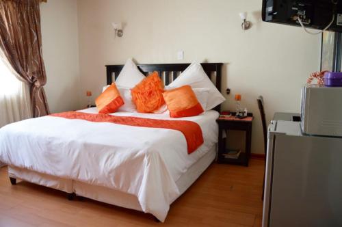 乌姆塔塔Shoes Guest House的卧室配有带橙色枕头的大型白色床