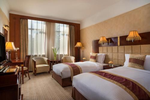西安西安豪华美居人民大厦的酒店客房配有两张床和一张书桌