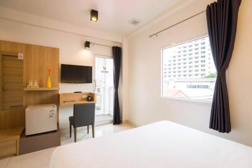 芭堤雅市中心Bedtime Pattaya的一间卧室配有一张床、一张书桌和一个窗户。
