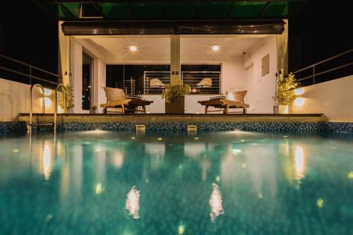 科伦坡Lavonca Boutique Hotel的夜间游泳池,配有桌椅