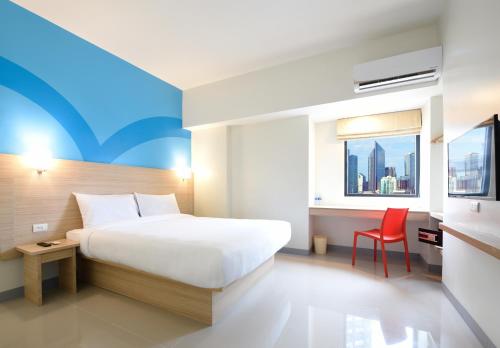 马尼拉Hop Inn Hotel Tomas Morato Quezon City的酒店客房,配有一张床和一张红色椅子