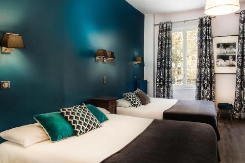 图尔米拉波酒店的蓝色墙壁客房的两张床