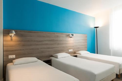 讷韦尔The Originals City, Hôtel Nevers Centre Gare (Inter-Hotel)的一间设有三张床和蓝色墙壁的房间