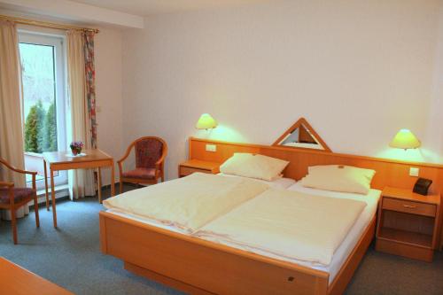 布里隆Hotel Haus Hellhohl Garni的一间卧室配有一张床、一张桌子和一张桌子