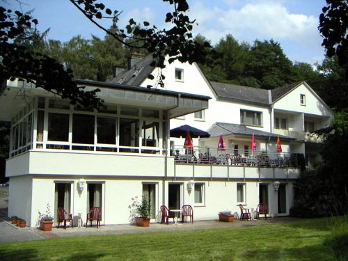 布里隆Hotel Haus Hellhohl Garni的一座白色的大建筑,前面设有桌椅