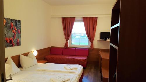 特赖斯基兴OEKOTEL Traiskirchen的酒店客房带两张床和一张红色沙发