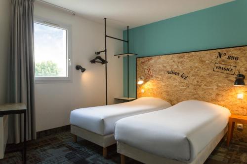 沙托盖The Originals Access, Hôtel Clermont-Ferrand Nord的酒店客房设有两张床和窗户。