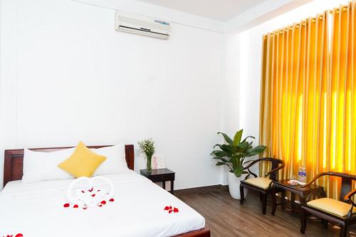 顺化Hue Royal Hotel的一间卧室配有床、椅子和黄色窗帘