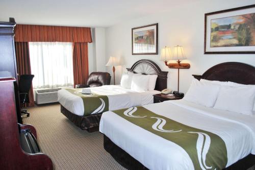 苏福尔斯苏福尔斯品质套房酒店的酒店客房,配有两张床和椅子