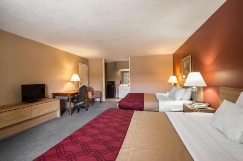 格林维尔Greeneville Inn And Suites的酒店客房配有两张床和一张书桌