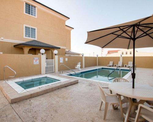 圣安吉洛Comfort Suites San Angelo near University的游泳池配有遮阳伞、桌子、桌子和遮阳伞