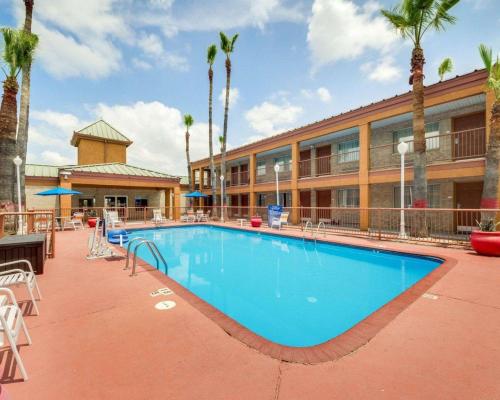 伊格尔帕斯Econo Lodge Inn & Suites的棕榈树建筑前的游泳池