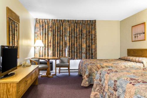 WaterfordRodeway Inn Waterford - New London的酒店客房设有两张床、一张桌子和一台电视。