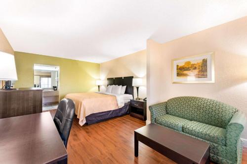奥兰多Quality Inn & Suites Orlando Airport的酒店客房配有床、沙发和桌子。