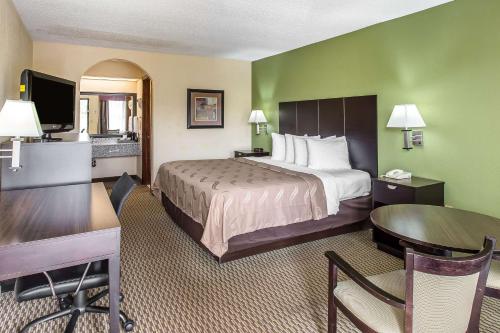AdairsvilleQuality Inn Adairsville-Calhoun South的配有一张床和一张书桌的酒店客房
