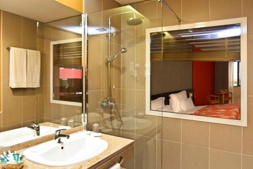 普拉亚Pestana Tropico Ocean & City Hotel的浴室配有盥洗盆和带镜子的淋浴