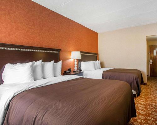 瓦恩兰Quality Inn Vineland的橙色墙壁的酒店客房内的两张床