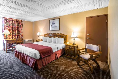 陶斯陶斯品质酒店的酒店客房带一张大床和一把椅子