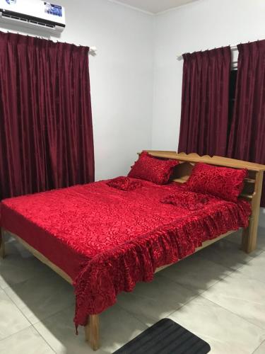 Nieuw NickerieZeedijk Resort Nickerie的一间卧室配有红色的床和勃 ⁇ 第窗帘