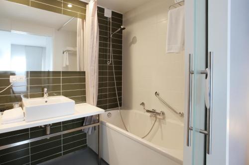赫斯登-佐尔德尔皮茨酒店的浴室配有盥洗盆、浴缸和镜子