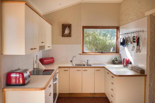 林道滨江农场度假屋的厨房配有白色橱柜和红色用具