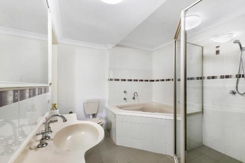 科夫斯港海滩走私者酒店的白色的浴室设有浴缸和水槽。