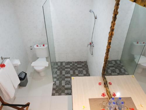 努沙杜瓦棕榈竹酒店的一间带卫生间和玻璃淋浴间的浴室