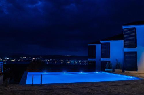 约阿尼纳La Suite Boutique Hotel & Spa的一座蓝色的游泳池,晚上与大楼相连