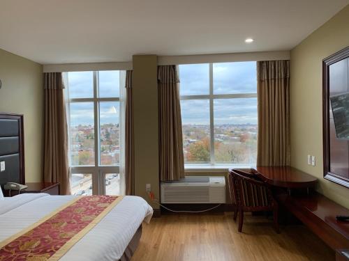 皇后区女皇酒店的酒店客房设有一张床、一张书桌和大窗户