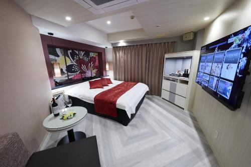 大阪Hotel Sen (Adult Only)的配有一张床和一台平面电视的酒店客房