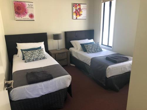 怀阿拉阳光庄园客栈&旅游假日公园的一间卧室配有两张带枕头的床。