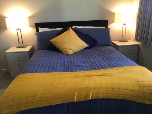 新普利茅斯Treetops On Heta的一张带蓝色和黄色床单的床和两盏灯