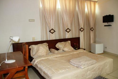 科托努Amazing Grace Residence的一间卧室配有一张带桌子和台灯的床