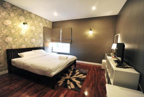 慕斯Kenora Khaoyai Retreats - Private Pool Villa的一间卧室配有一张床和一台电视